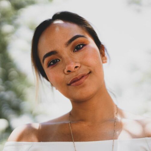 woman with dark brows and lashes smiles